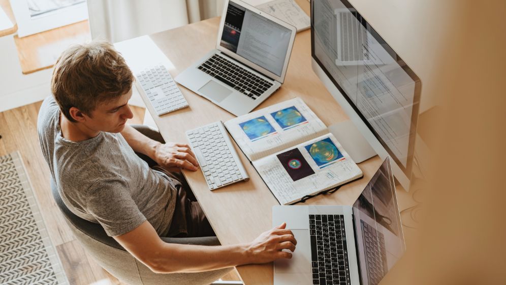 Man working on two laptops at home