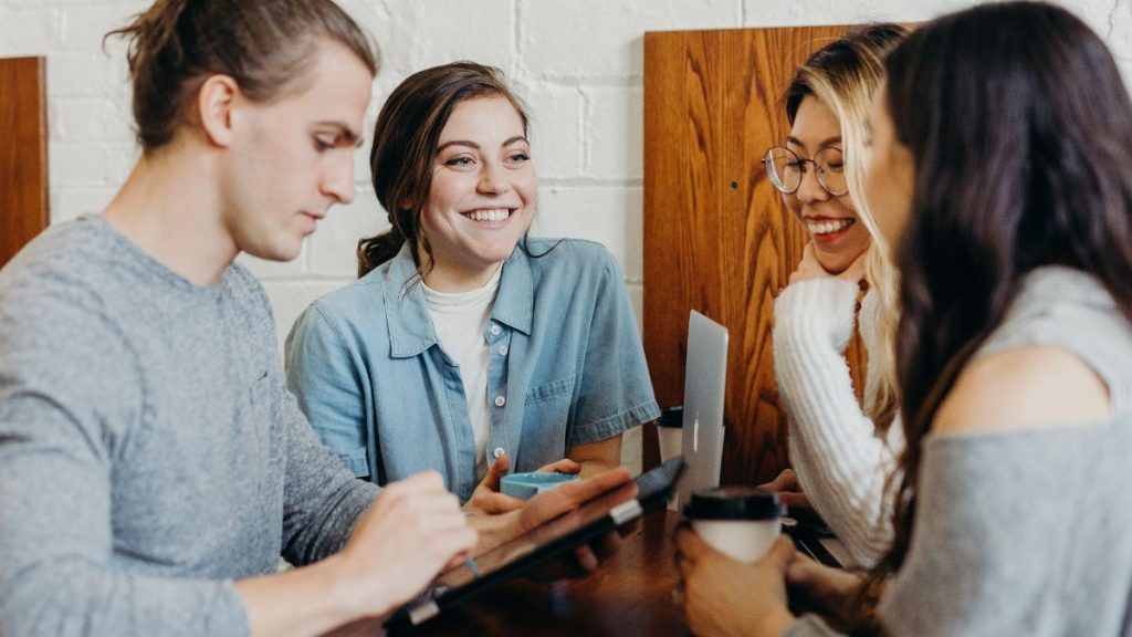 3 woman and 1 man working together on tablets