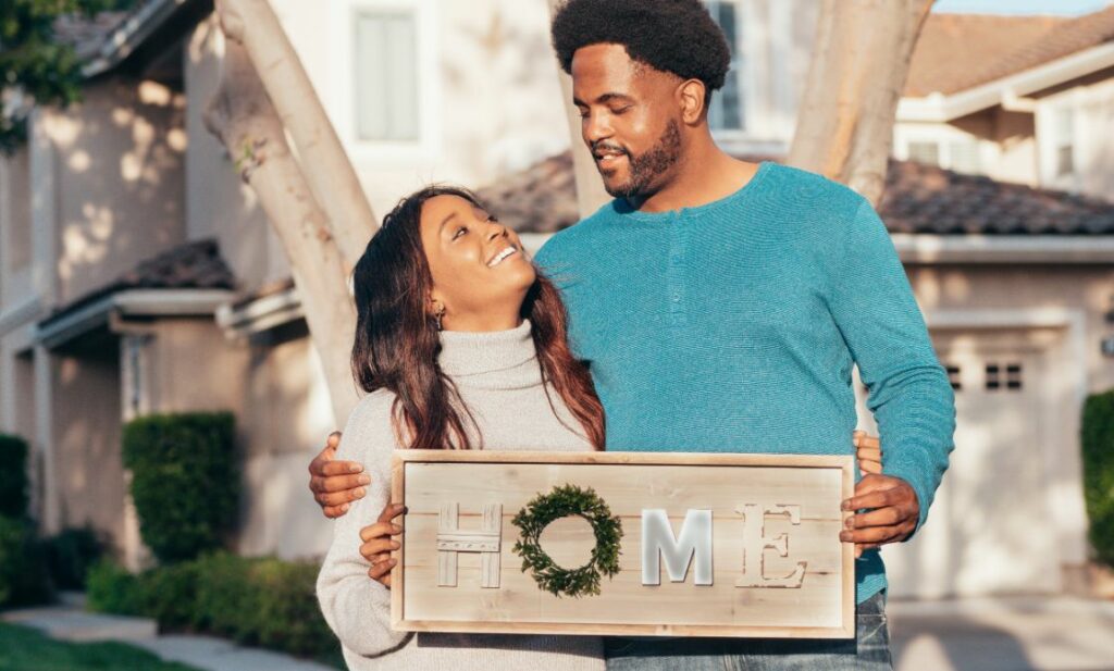 Man and woman holding sign that reads HOME