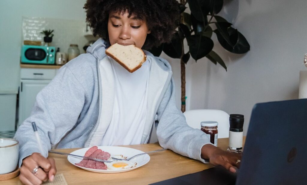 Woman eating while working at laptop