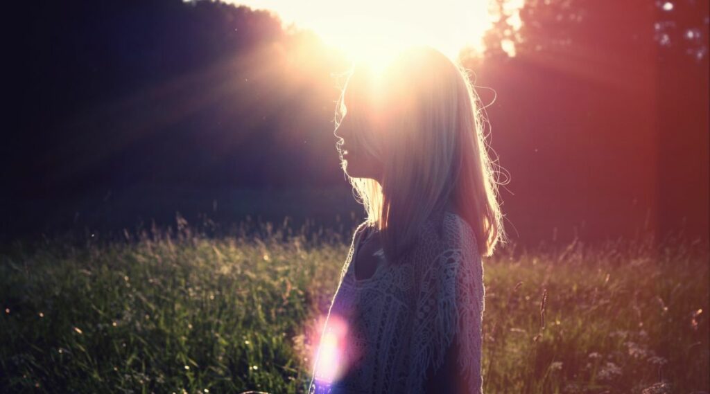 Woman outside with sun reflecting behind her