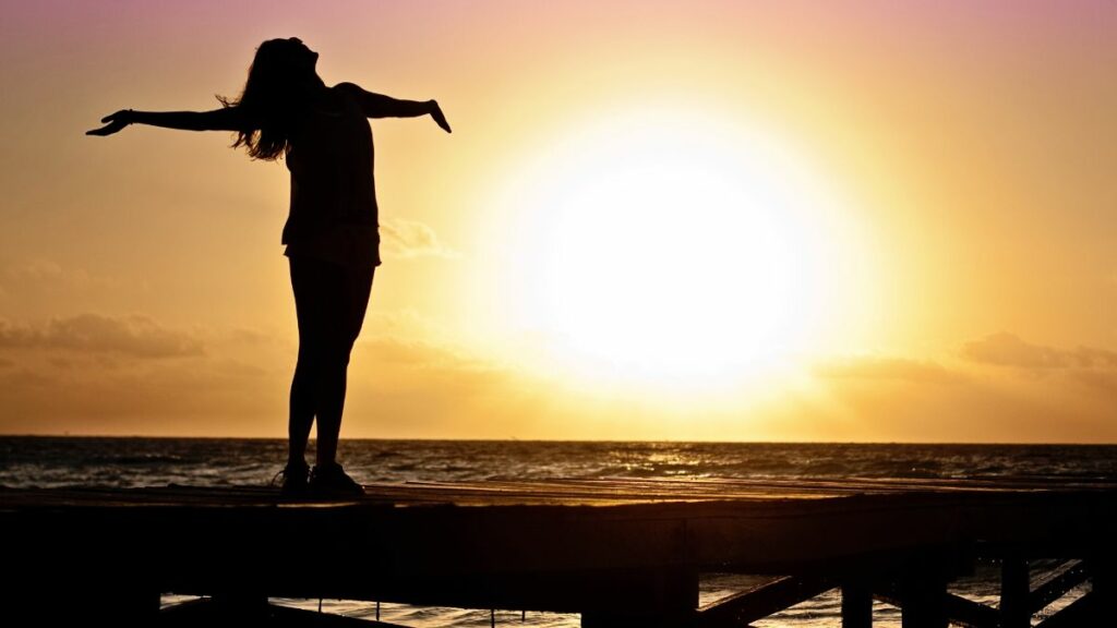 Silhouette of woman on beach at sunrise