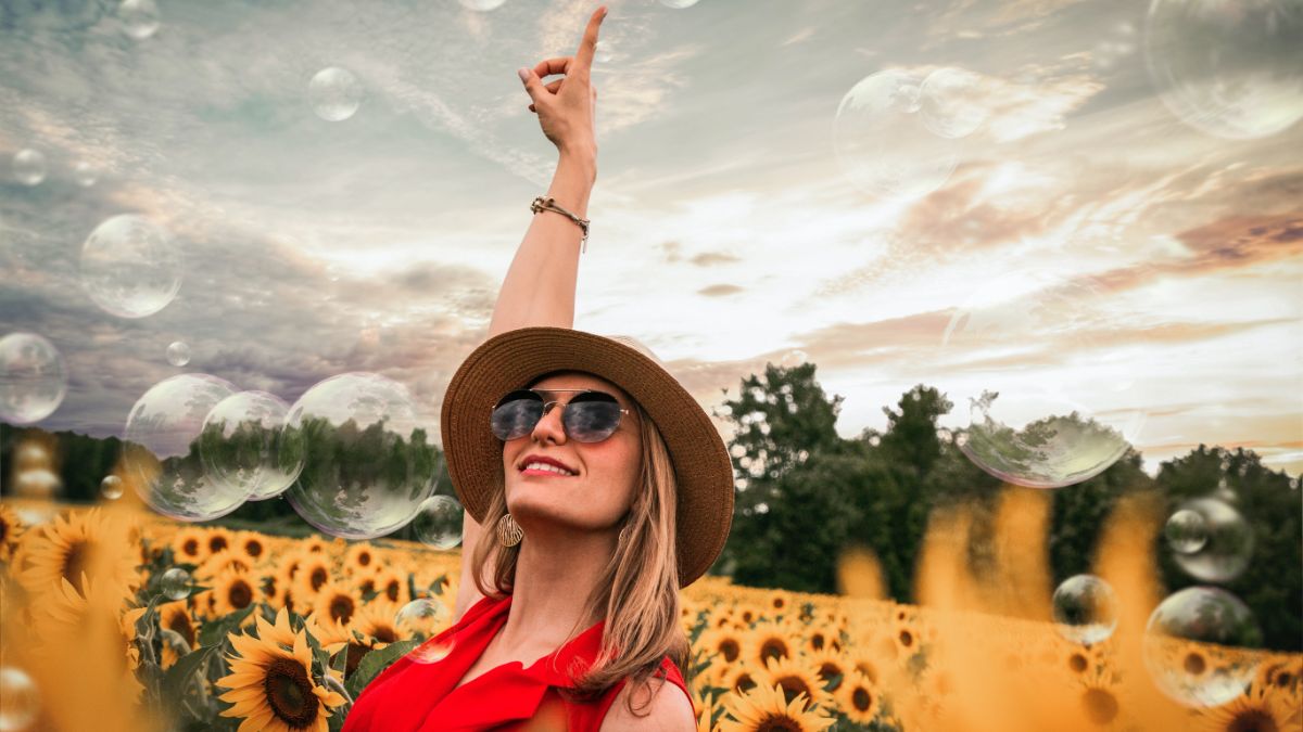 Happy woman in sunflower field pointing to sky