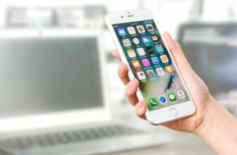 Hand holding phone with apps on home screen
